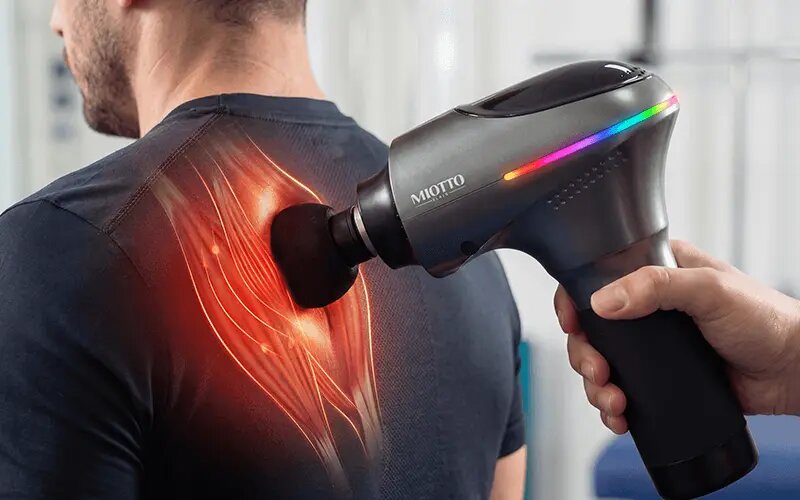 فردی در حال استفاده از ماساژور تفنگی میوتو برای نقاط ماشه ای