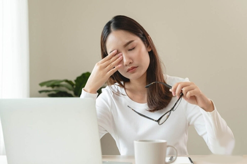 زنی که دچار خستگی مزمن ناشی از اضطراب است و چشم خود را میخاراند